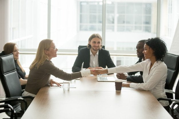 diverse-smiling-businesswomen-shaking-hands-greeting-multiracial-group-meeting_1163-4650